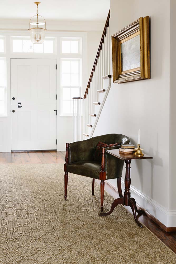transitional style entry way with antique furniture and a sisal rug in tan color