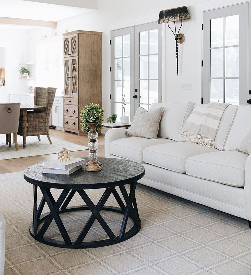 white sofa in a farmhouse style living room with a plaid wool rug in neutral colros